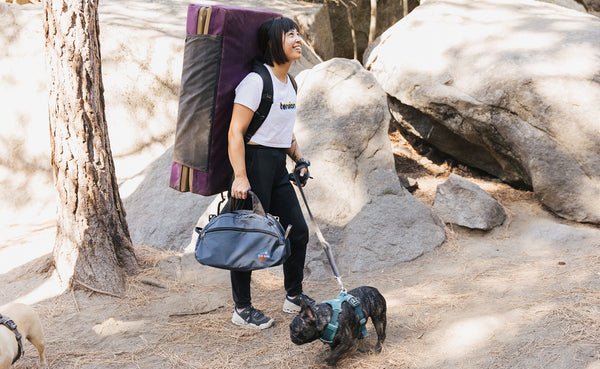 Person at a climbing area walking their dog on leash and carrying the Old-School Carry All.